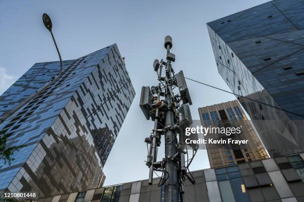 Chinese technician wears a protective mask as he installs a new Huawei 5G station on a tower in a business district on April 23, 2020 in Beijing,...