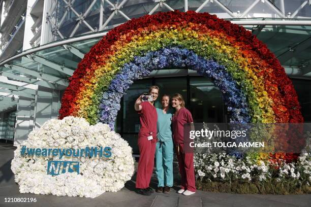 Doctors from University College Hospital pose for a photograph at a floral rainbow tribute to NHS staff providing essential services during the...