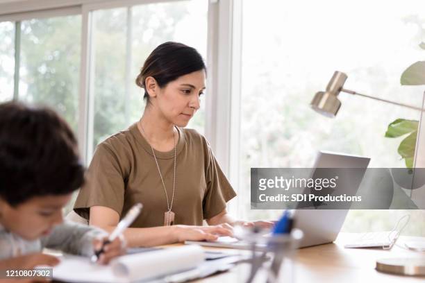 mid adult female soldier works on home finances - armed forces stock pictures, royalty-free photos & images
