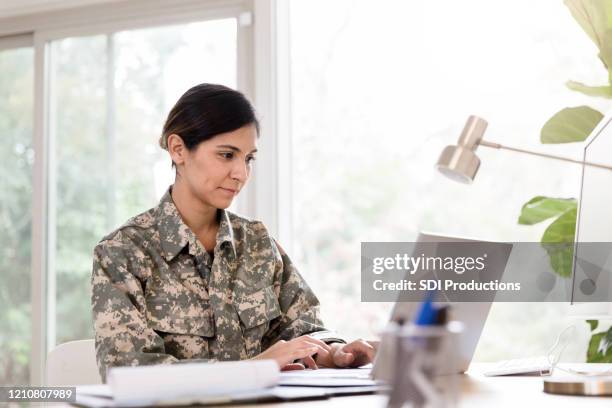 mid adult female soldier works remote from home office - people in military uniform stock pictures, royalty-free photos & images