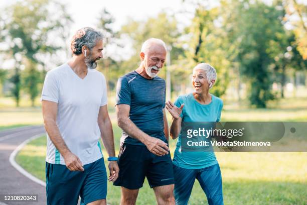 smiling senior athletes jogging in the park - 3 old men jogging stock pictures, royalty-free photos & images