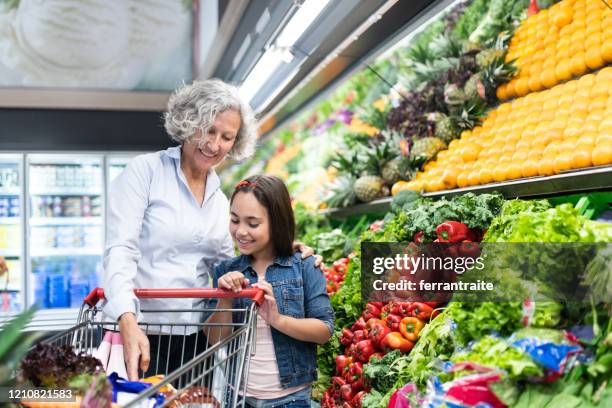 granddaughter helping grandmother shopping in supermarket - grandmother granddaughter stock pictures, royalty-free photos & images