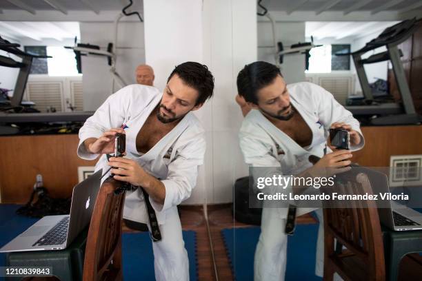 Venezuelan Karateka Antonio Jose Diaz Fernandez prepares a cell phone before starting his online karate lessons from his dojo during COVID-19...