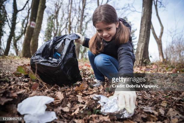 ragazza che raccoglie rifiuti nei boschi - sollevare foto e immagini stock