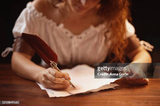 young woman with with long wavy red hair wearing ruched white lace-up blouse writing with quill pen, studio shot, cropped below eyes - white blouse stock pictures, royalty-free photos & images