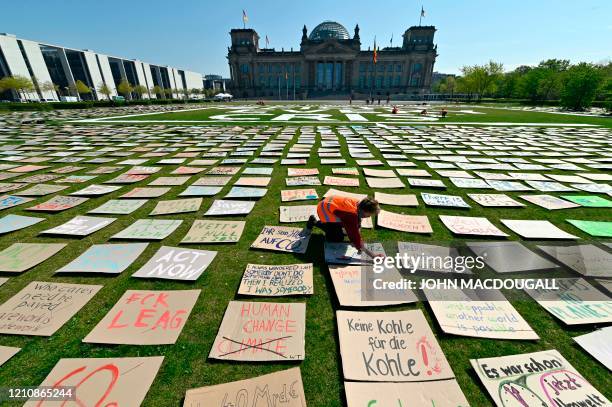 Fridays for Future" climate activist places hand-painted posters calling for climate change on the meadow in front of the Reichstag building as part...
