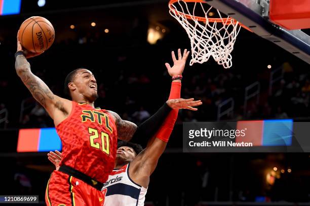John Collins of the Atlanta Hawks dunks over Rui Hachimura of the Washington Wizards during the first half at Capital One Arena on March 06, 2020 in...