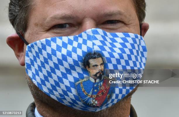 Participant of a protest action of gastronomers wears a face mask in the colors of Bavaria and depicting former Bavarian King Ludwig II at the...