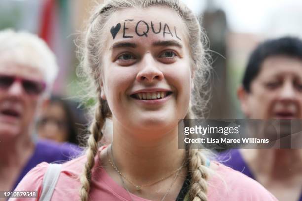 Woman smiles with the word 'equal' written on her forehead as she gathers in Hyde Park during the Sydney International Women's Day march on March 07,...