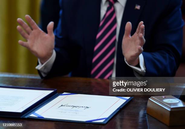 President Donald Trump gestures as he speaks after signing the Paycheck Protection Program and Health Care Enhancement Act in the Oval Office of the...