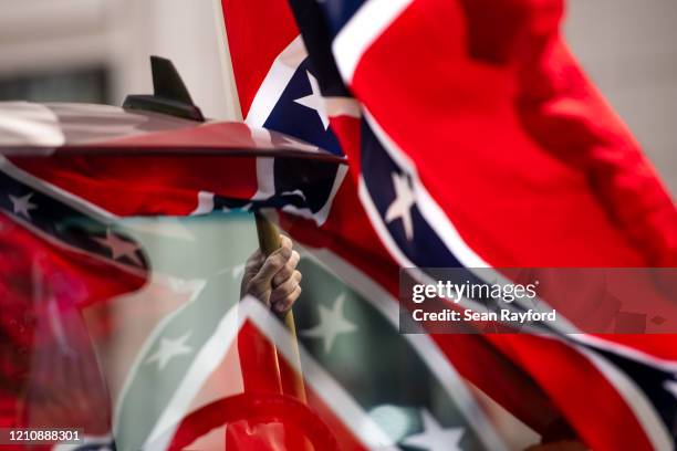 Man holds a Confederate flag while participating in a protest against government closures of non-essential businesses due to the coronavirus on April...