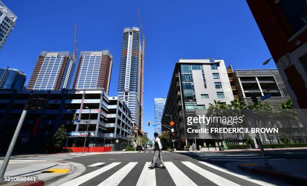Pedestrian crosses the street near towering blocks of highrise buildings for residential and commerical use near the Staples Center in Los Angeles,...