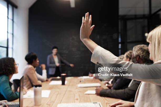 businesswoman with hand raised in conference room - chiedere foto e immagini stock