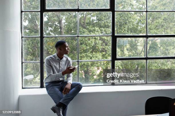 businessman with phone looking away at workplace - in die ferne schauen stock-fotos und bilder