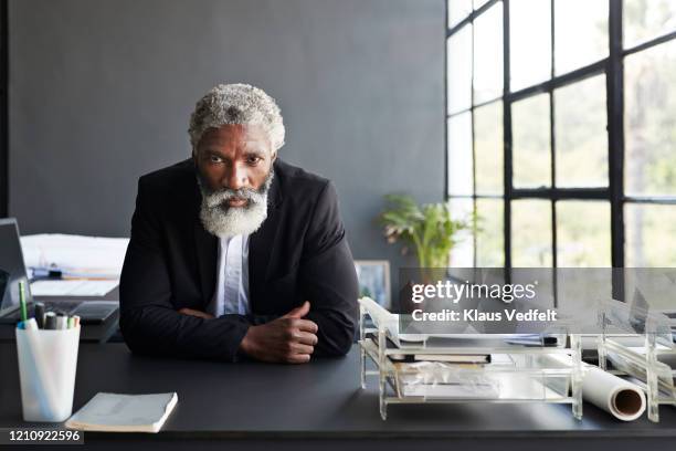 serious entrepreneur sitting at desk in office - hard fotografías e imágenes de stock