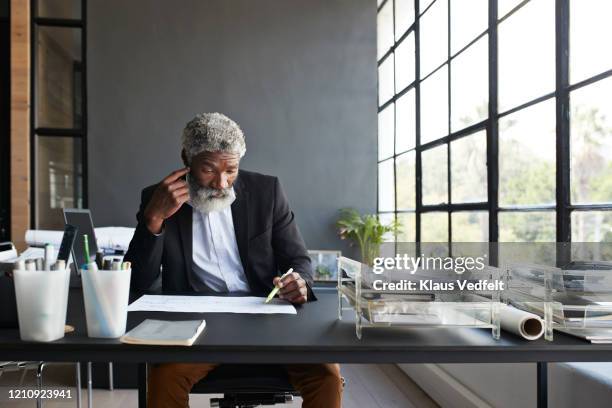 contemplating businessman working at office desk - examining paperwork stock pictures, royalty-free photos & images