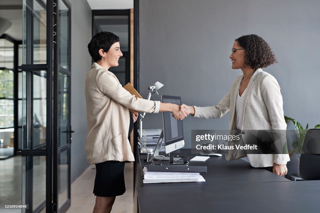 Businesswomen shaking hands in modern office