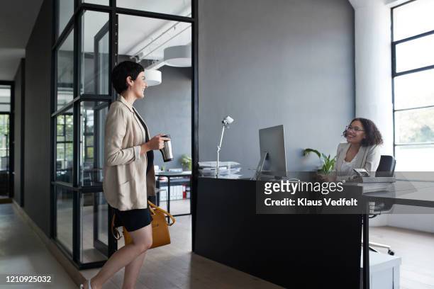 businesswoman talking to coworker in office - cream colored jacket stock pictures, royalty-free photos & images