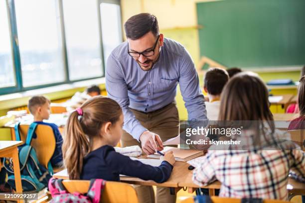年輕的快樂教授説明他的小學生在學校上課。 - elementary age 個照片及圖片檔