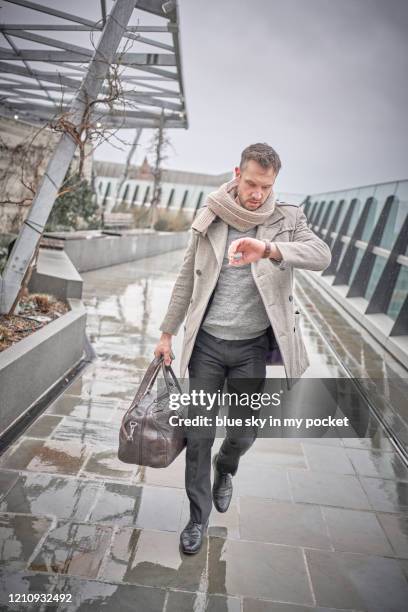 a smart casual business man walking through the rain, checking the time - casual menswear stock pictures, royalty-free photos & images