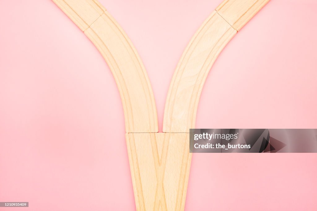 High angle view of wooden railroad tracks on pink background
