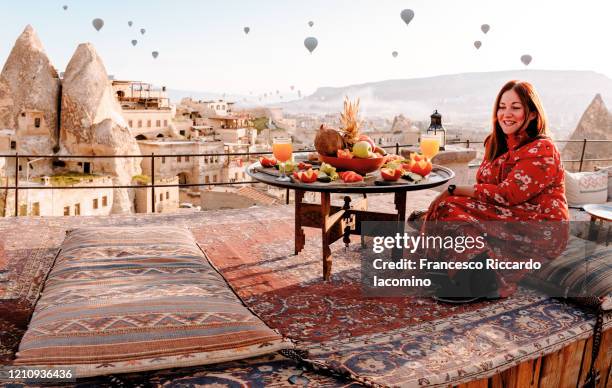 woman dressed in red on a rooftop in cappadocia at sunrise, turkey - capadócia imagens e fotografias de stock