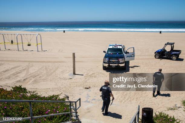 Two Manhattan Beach Police officers walk back to their vehicles after issuing tickets to two people who violated the California Health and Safety...