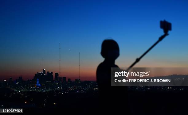 Selfie-stick is used for cellphone photos after sunset in Los Angeles, California on April 24, 2020. - A ridge of high pressure is bringing the first...