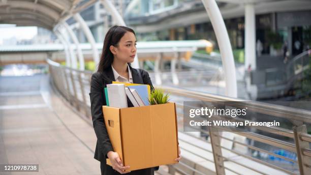 businesswoman leaving office with box of personal items - rauswerfen stock-fotos und bilder