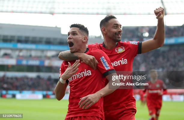 Paulinho of Bayer 04 Leverkusen celebrates with teammate Karim Bellarabi after scoring their team's fourth goal during the Bundesliga match between...