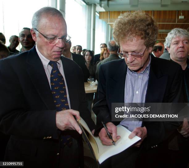 Ancien entraîneur de de l'équipe de football de Saint-Etienne Robert Herbin signe un autographe au journaliste de télévision Thierry Roland lors...