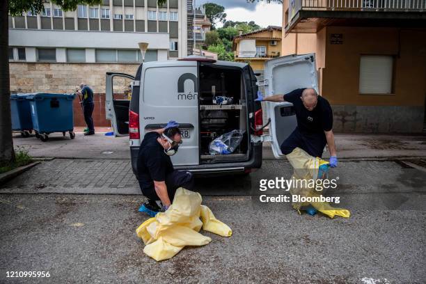 Workers dress in personal protective equipment to collect the body of a victim of coronavirus from a nursing home, to take to the Memora Servicios...