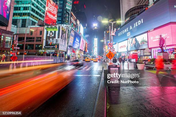 Night view of Times Square in Manhattan, New York City, USA during light rain showers in the night. Times Square is a major commercial intersection,...