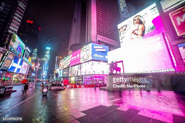 Night view of Times Square in Manhattan, New York City, USA during light rain showers in the night. Times Square is a major commercial intersection,...