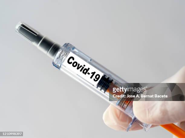 a doctor's hand with a syringe of covid-19 vaccine. - crime or recreational drug or prison or legal trial stock-fotos und bilder