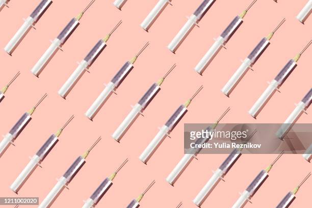 repeated syringes on the pink background - flu vaccination stock pictures, royalty-free photos & images