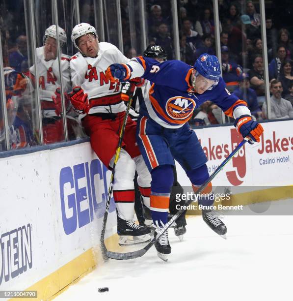 Ryan Pulock of the New York Islanders checks Justin Williams of the Carolina Hurricanes into the boards during the first period at NYCB Live's Nassau...