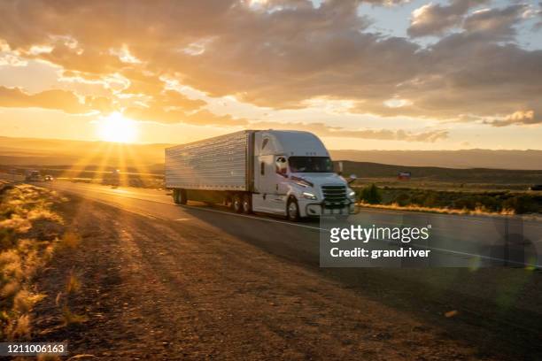 long haul semi truck speeding down a four lane highway to delivery heavy cargo - semi truck stock pictures, royalty-free photos & images
