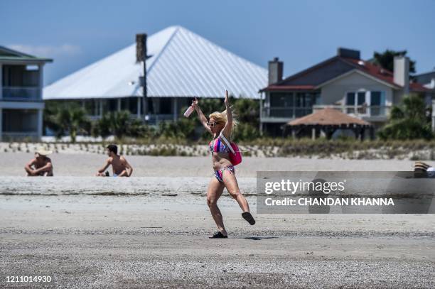 Woman dances amid the Coronavirus pandemic on the Tybee Beach in Tybee Island, Georgia on April 25, 2020. - After being locked down for weeks, many...