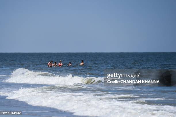 People relax in the water on the Tybee Beach in Tybee Island, Georgia on April 25, 2020. - After being locked down for weeks, many residents in...