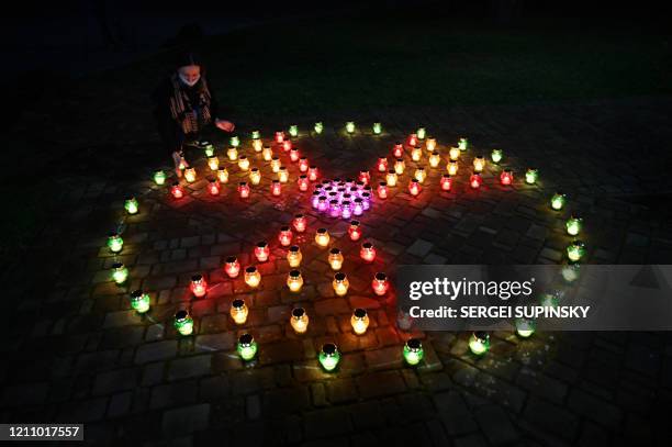 Girl wearing a face mask places a candle amongst others forming a radioactivity sign at the monument to Chernobyl victims in Slavutich, the city...