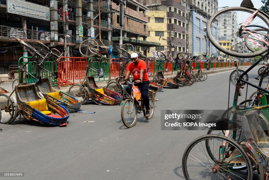 A man rides past a line of inverted rickshaws on the street...