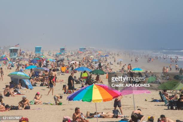 People enjoy the beach amid the novel coronavirus pandemic in Huntington Beach, California on April 25, 2020. - Orange County is the only county in...