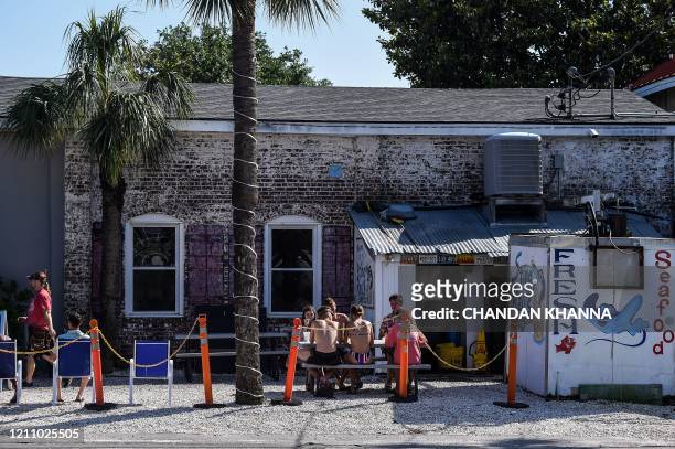 People sit and eat at a road side food joint amid the novel coronavirus pandemic in Tybee Island, Georgia, on April 25, 2020. - After being locked...