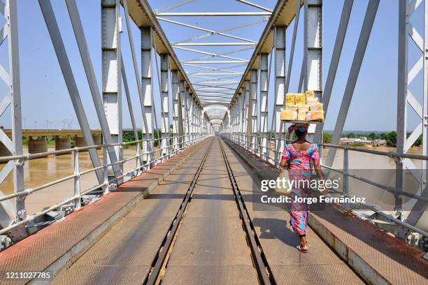 Woman with a load on her head crossing river Niger using the railway bridge at Jebba.