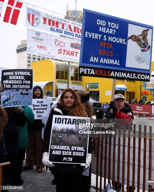 Activists of the animal rights organization PETA protest against the use of dogs in racing while an anti-PETA demonstrator holds up a sign prior to...