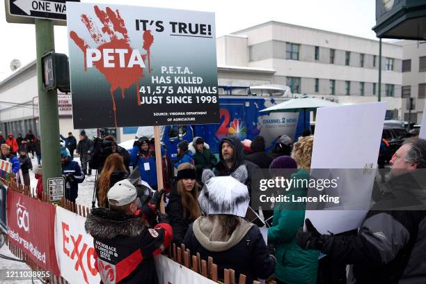 Activists of the animal rights organization PETA protest against the use of dogs in racing while an anti-PETA demonstrator holds up a sign prior to...