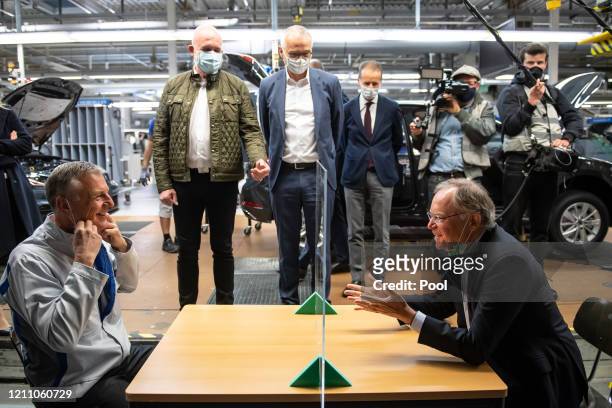 Stephan Weil , Prime Minister of Lower Saxony, and Stefan Loth, the plant manager, sit at a table in production that is divided with a plexiglass...