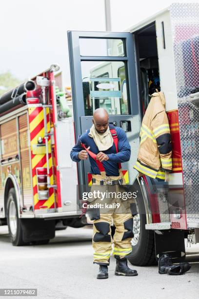 firefighter putting on fire protection suit - firefighter getting dressed stock pictures, royalty-free photos & images