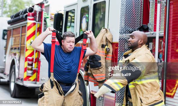 firefighters putting on fire protection suits - firefighter getting dressed stock pictures, royalty-free photos & images